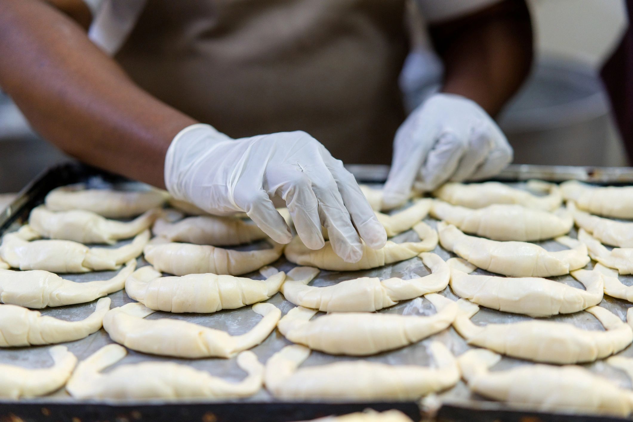 Hands shaping pastry dough on a work surface